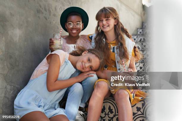 group shot of 3 girlfriends sitting on staircase - klaus vedfelt stock-fotos und bilder