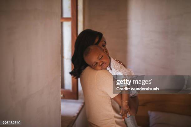 young mother at home rocking baby to sleep with lullaby - mom and baby sleeping stock pictures, royalty-free photos & images