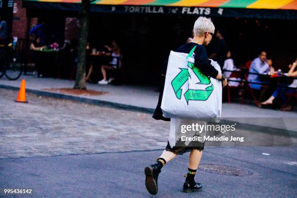 Guest in a "Bag for life" recycling tote bag during New York Fashion Week Mens Spring/Summer 2019 on July 9, 2018 in New York City.