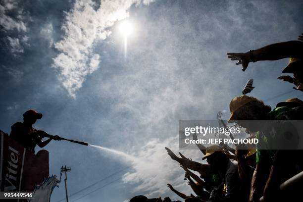 Woman form the publicity caravan sprays refreshing water on spectators waiting at the finish line to watch the arrival of the fourth stage of the...