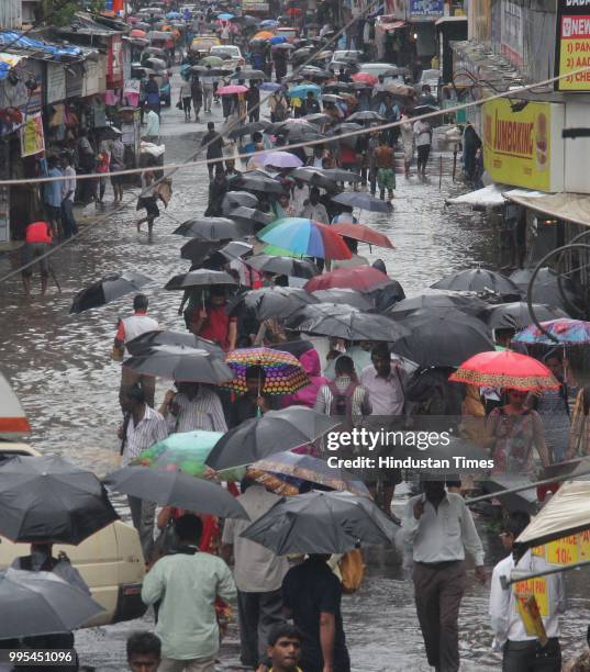 People wade through water-logged on streets after heavy rainfall, at Dadar, on July 9, 2018 in Mumbai, India. Indias financial capital and its...