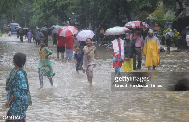 People wade through water-logged on streets after heavy rainfall, at Dadar, on July 9, 2018 in Mumbai, India. Indias financial capital and its...