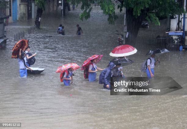 People wade through water-logged on streets after heavy rainfall, at Parel, on July 9, 2018 in Mumbai, India. Indias financial capital and its...