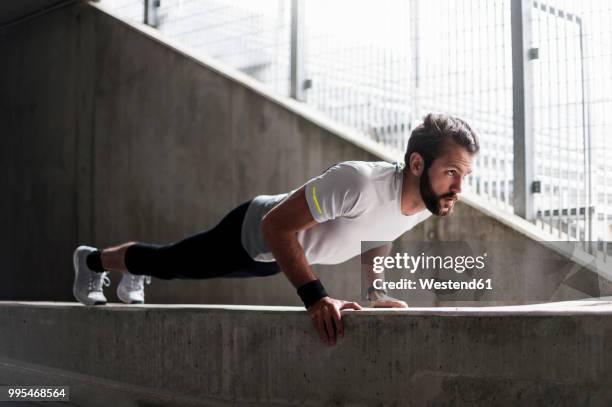 man doing push-ups on concrete wall - flexiones fotografías e imágenes de stock
