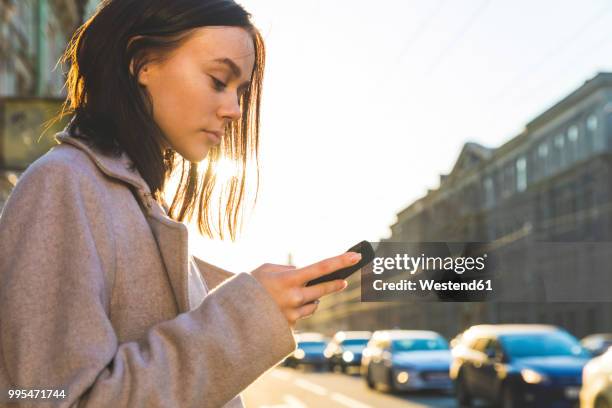 russia, st. petersburg, young woman using smartphone in the city - women phone city facebook tourist stock pictures, royalty-free photos & images