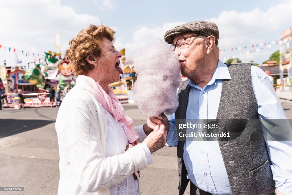 Senior couple on fair eating together cotton candy