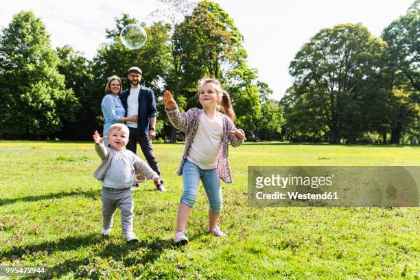 happy family playing with soap bubble in a park - child animated watching stock-fotos und bilder