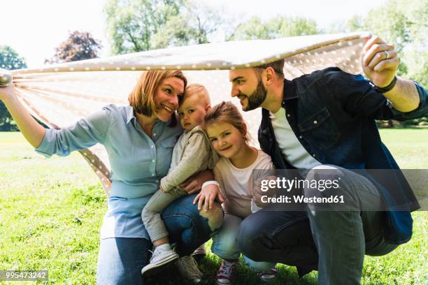 happy family under a blanket in a park - beschützer stock-fotos und bilder