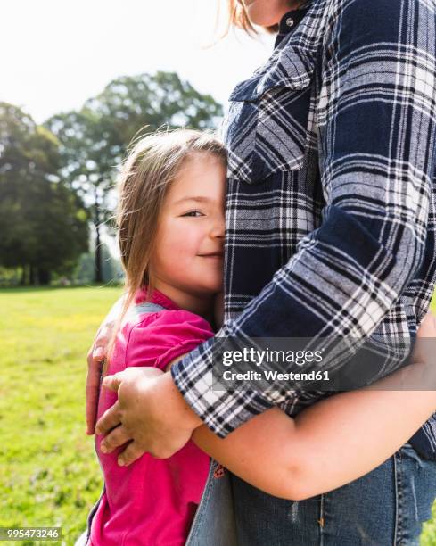 daughter hugging mother in a park - beschützer stock-fotos und bilder