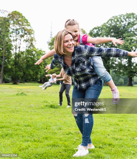 active happy family in a park - woman child piggyback stock-fotos und bilder