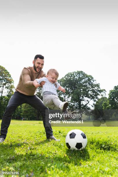 happy father playing football with son in a park - german film ball 2018 stock-fotos und bilder