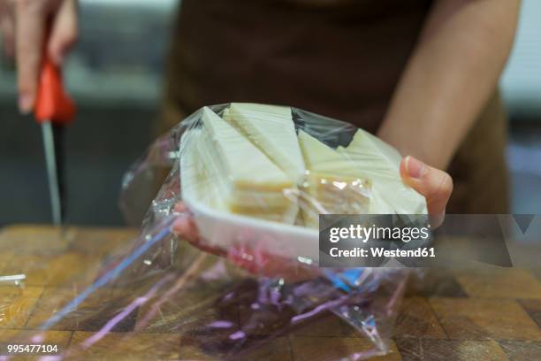 saleswoman packing cheese in bowl with clingfilm - polyäthylen stock-fotos und bilder