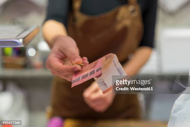 butchery, female butcher with change - paying with money stockfoto's en -beelden