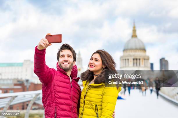 uk, london, portrait of smiling young couple taking selfie with cell phone in front of st pauls cathedral - red coat stock pictures, royalty-free photos & images