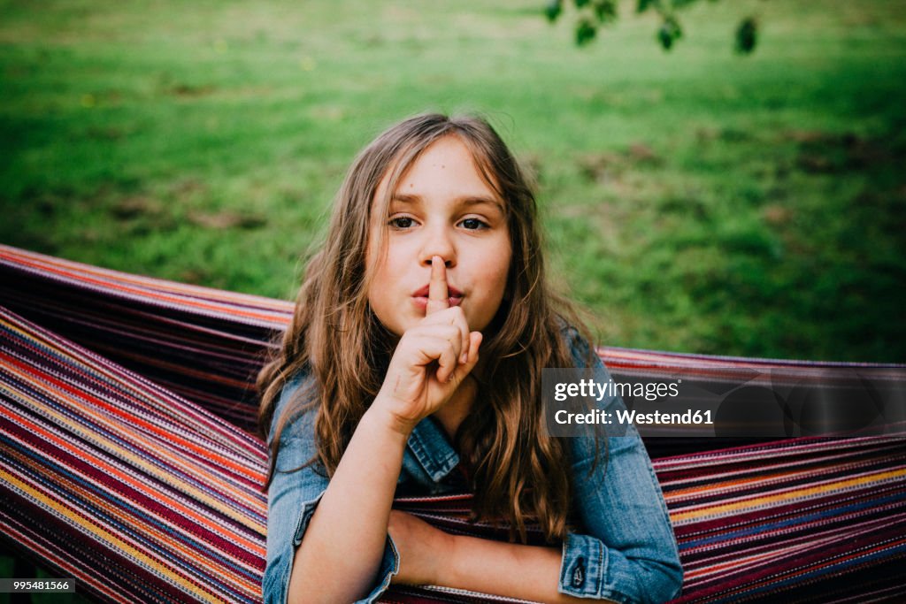 Portrait of girl in hammock with finger on her mouth