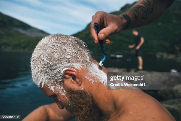 norway, lofoten, traveller getting his head shaved at lake - shaved head ストックフォトと画像