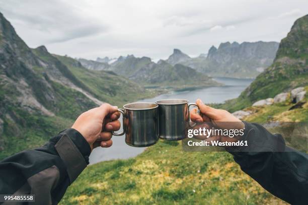 norway, lofoten, moskenesoy, two people toasting with tin cups - moskenesoya stock pictures, royalty-free photos & images