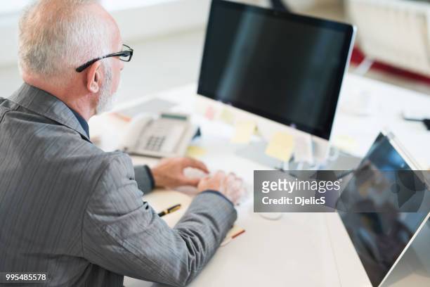 mature, homme d’affaires travaillant dans sa vue arrière du bureau. - directeur d'exploitation photos et images de collection