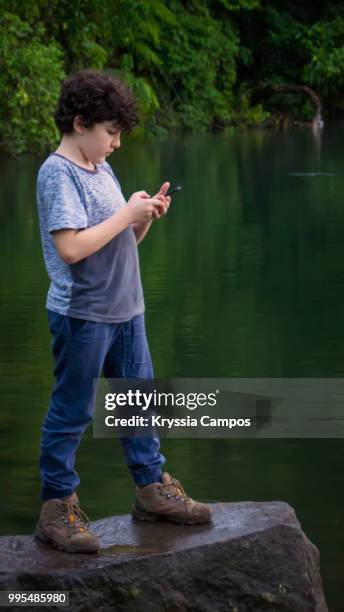 boy using mobile phone at tropical rainforest - alajuela stockfoto's en -beelden