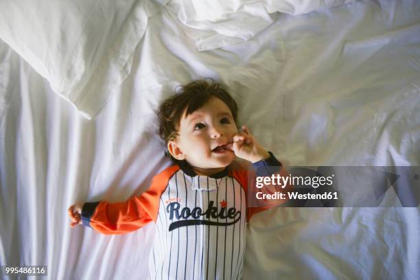 portrait of baby girl wearing jumpsuit lying on bed - one baby girl only stock pictures, royalty-free photos & images