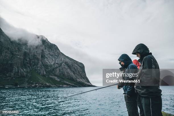 norway, lofoten, moskenesoy, young men fishing at horseid beach - moskenesoya stock pictures, royalty-free photos & images