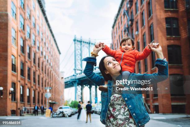 usa, new york, new york city, mother and baby in brooklyn with manhattan bridge in the background - new york city fotografías e imágenes de stock