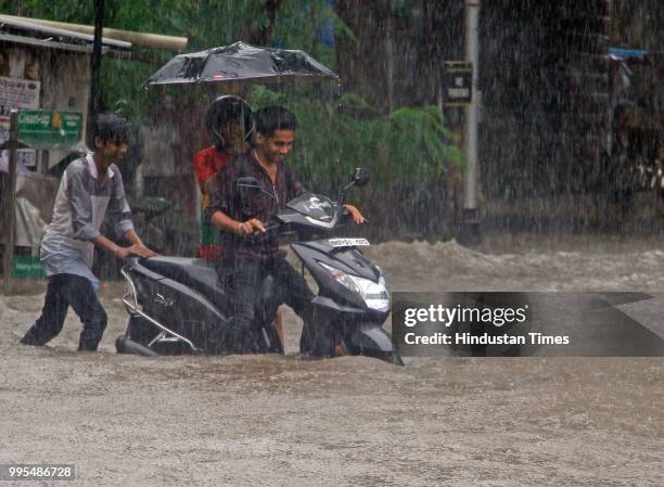 People deal with heavy rain and water logging towards Dadar East Station on July 9, 2018 in Mumbai, India. Indias financial capital and its...