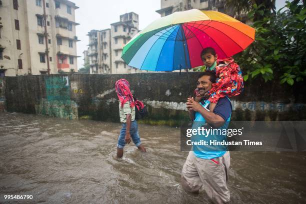 People make their way through the waterlogged road as it rains very heavily near Tilak Nagar railway station on July 9, 2018 in Mumbai, India. Indias...