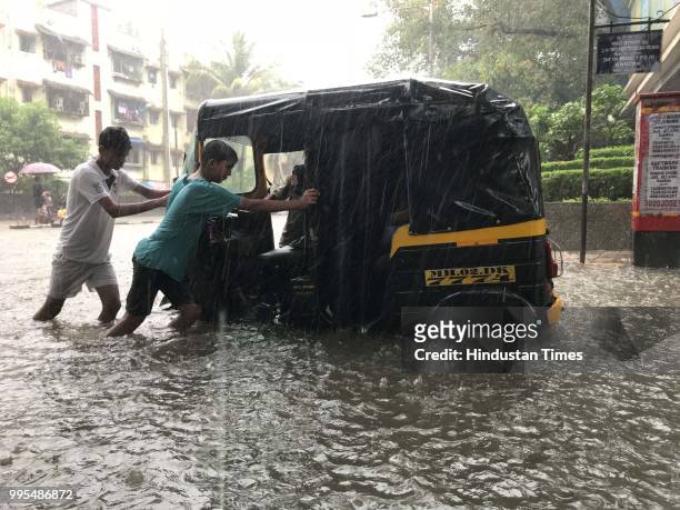 Boys push auto rickshaw which had stopped on a waterlogged street at KharSV road during heavy rainfall on July 9, 2018 in Mumbai, India. Indias...