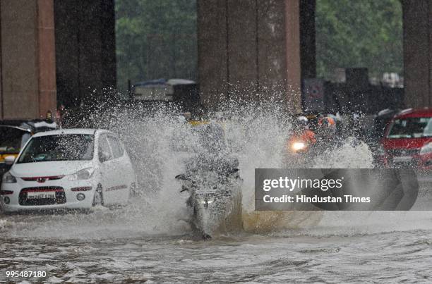 Vehicles and people wade through waterlogged street on WEH at Jogeshwari on July 9, 2018 in Mumbai, India. Indias financial capital and its...