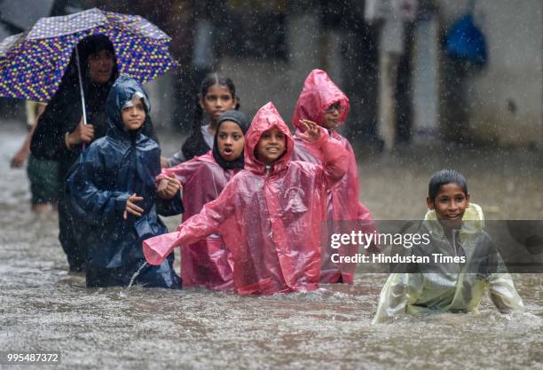 People wades through a water logged street as it rains at Sion on July 9, 2018 in Mumbai, India. Indias financial capital and its surrounding...