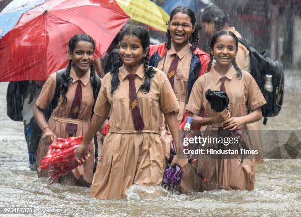 People wades through a water logged street as it rains at Sion on July 9, 2018 in Mumbai, India. Indias financial capital and its surrounding...