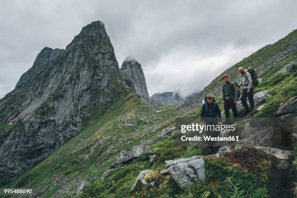 norway, lofoten, moskenesoy, young men hiking at markan mountain - moskenesoya stock pictures, royalty-free photos & images