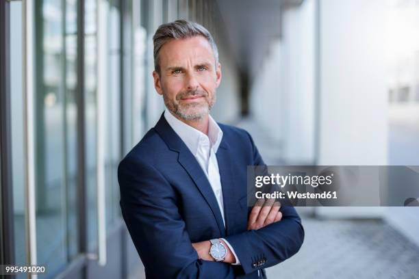 portrait of businessman wearing blue suit coat and wrist watch - modern maturity center foto e immagini stock