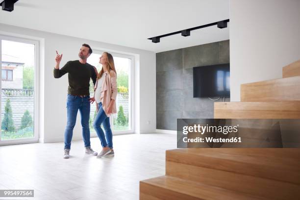 couple looking around in empty flat - visie photos et images de collection