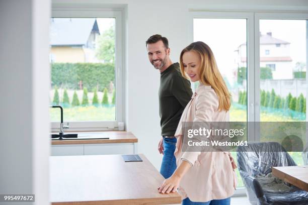 couple examining kitchen in new flat - mirar alrededor fotografías e imágenes de stock