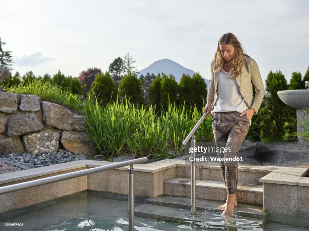 Woman testing the temperature at a Kneipp basin