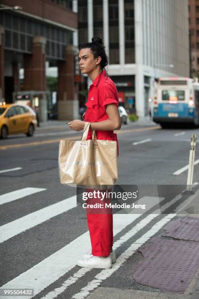 Guest in a red jumpsuit and Comme des Garcons bag uring New York Fashion Week Mens Spring/Summer 2019 on July 9, 2018 in New York City.