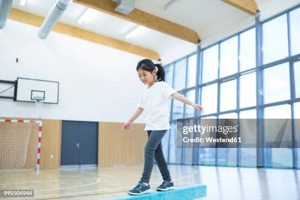 schoolgirl balancing on balance beam in gym class - school gymnastics stock pictures, royalty-free photos & images