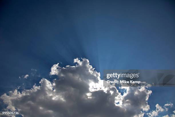 Heavenly shafts of light as sunlight creates shadow from behind a cloud at Broadway in The Cotswolds, United Kingdom. Particles in the air are picked...