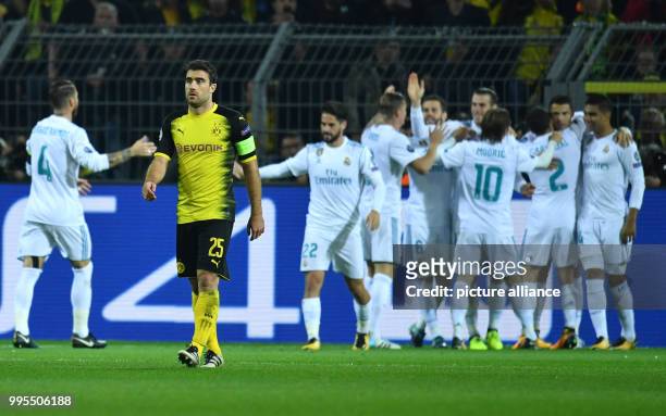 Dortmund's Sokratis walks across the pitch, as Madrid players celebrate the goal for 0:2 during the UEFA Champions League football match between...