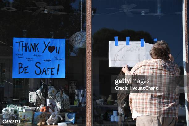 David Hood of Walsenburg puts sign of La Veta Mercantile at the window of the store. The Colorado Department of Transportation has closed Highway 160...