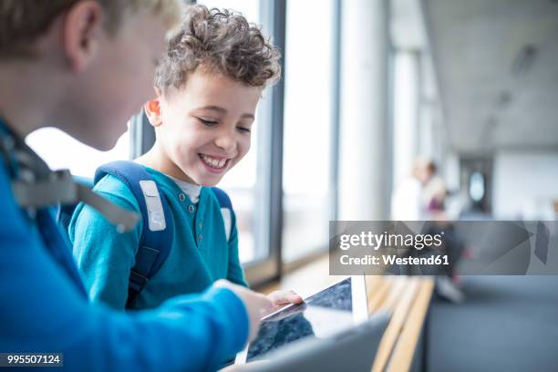 smiling pupils sharing a tablet on school corridor - school tablet stock-fotos und bilder