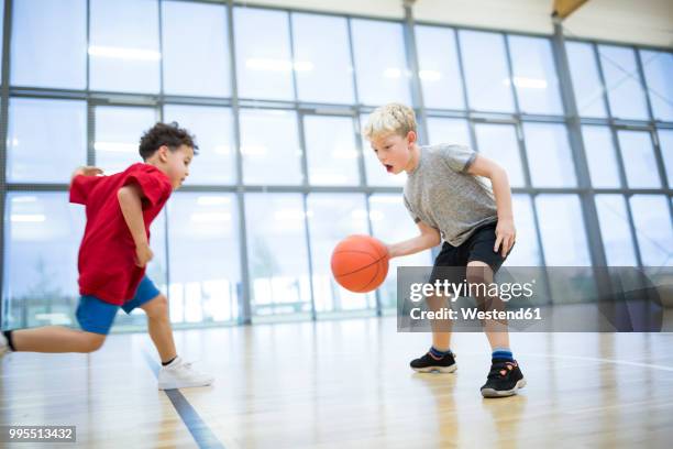 two schoolboys playing basketball in gym class - dribbling sport foto e immagini stock