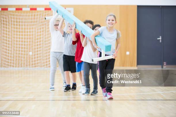 pupils carrying balance beam in gym class - school gymnastics stock-fotos und bilder