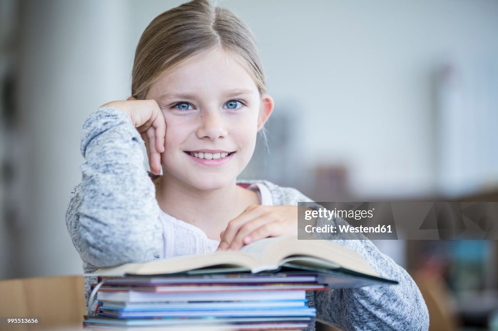 Portrait of smiling schoolgirl with books in school