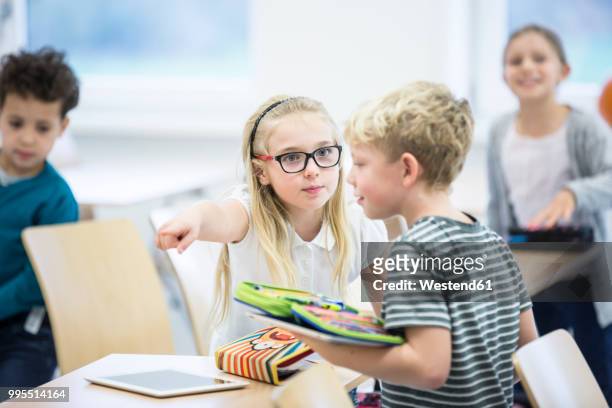 serious girl rebuking boy in class - bully school stock-fotos und bilder