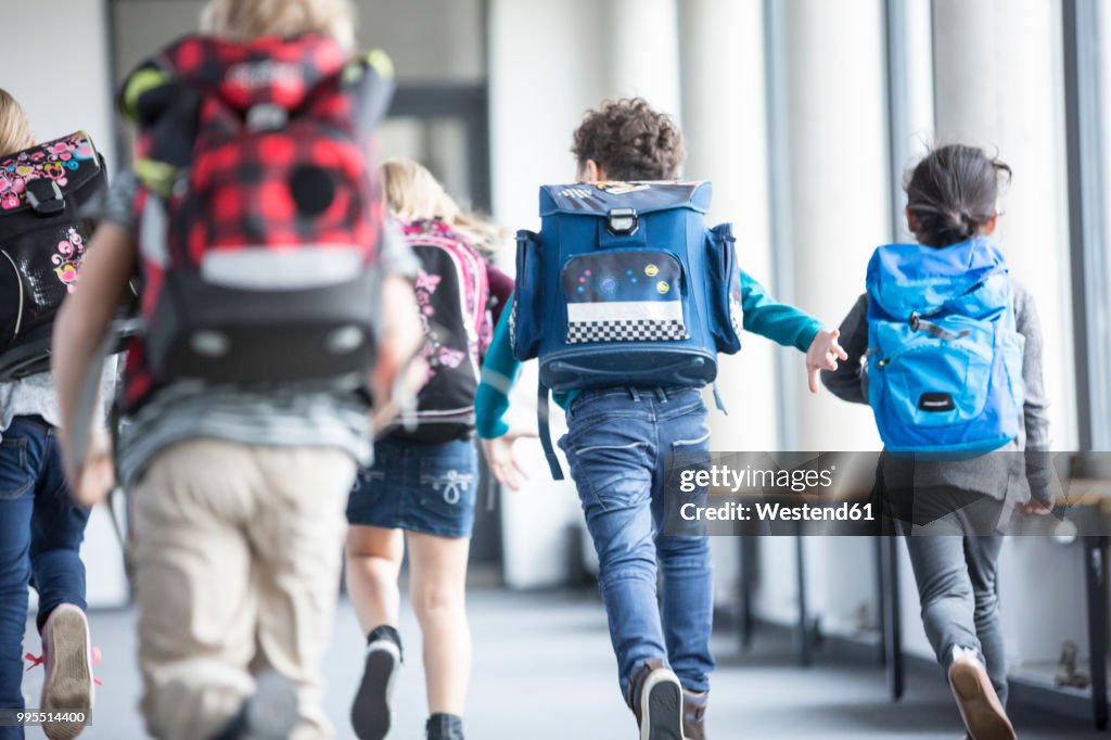 Rear view of pupils rushing down school corridor