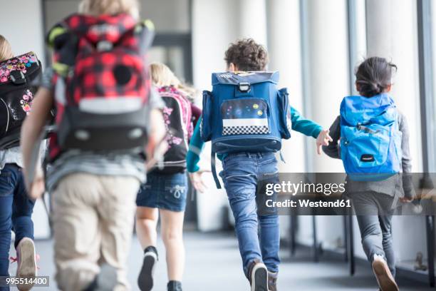 rear view of pupils rushing down school corridor - rucksacks stock-fotos und bilder