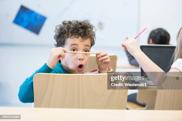 schoolboy in class staring at pencil - school boy girl stock-fotos und bilder